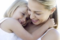 Mother and daughter cuddling and smiling outdoors. — Stock Photo