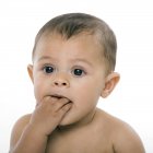 Teething baby girl holding hand in mouth. — Stock Photo