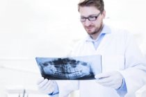 Zahnarzt betrachtet Röntgenbild — Stockfoto
