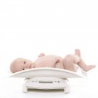 Baby lying down on weight scale. — Stock Photo