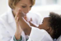 Female doctor playing with baby patient at examination in clinic. — Stock Photo