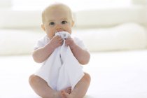 Baby girl chewing blanket on floor. — Stock Photo