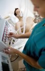 Krankenschwester passt Kontrollen an Beatmungsgerät an bewusstlosen Patienten an. — Stockfoto