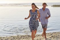 Couple running on beach and smiling. — Stock Photo