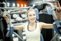 Woman using butterfly machine in gym. — Stock Photo