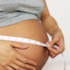 Vista recortada de la mujer embarazada que mide el abdomen hinchado . - foto de stock