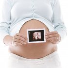 Pregnant woman holding baby scan printout. — Stock Photo