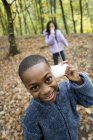 Niño y niña usando el teléfono de cuerda en el bosque en otoño . - foto de stock