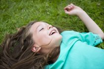 Молодая девушка лежит на траве и улыбается . — стоковое фото