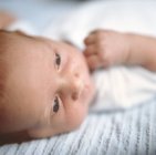 Close-up of baby boy lying on back in bed. — Stock Photo