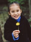Sorrindo menina pré-escolar segurando flor de dente de leão amarelo . — Fotografia de Stock