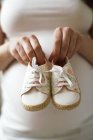 Pregnant woman holding baby shoes. — Stock Photo