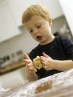 Niño preescolar rodando masa de galletas . - foto de stock