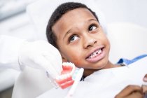 Крупним планом руки стоматолога показують хлопчику, як чистити зуби . — стокове фото
