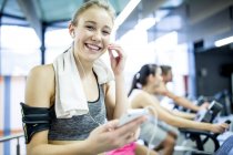 Woman adjusting earphones and listening to music while working out in gym. — Stock Photo