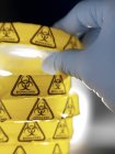 Scientist holding petri dish with biohazard warning in microbiology lab. — Stock Photo