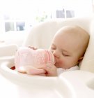 Sleeping baby girl holding bottle of milk in mouth. — Stock Photo