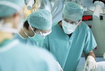 Chirurgien parlant à des collègues pendant l'opération en salle d'opération . — Photo de stock