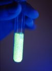 Gros plan du tube à essai à main de scientifique avec fluide chimique fluorescent . — Photo de stock