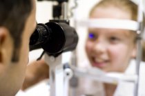 Óptico usando lámpara de hendidura para el examen ocular niña preadolescente . - foto de stock