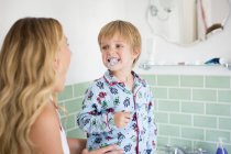 Pré-escolar filho escovar os dentes com a mãe no banheiro . — Fotografia de Stock