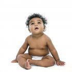 Baby girl sitting and looking up on white background. — Stock Photo