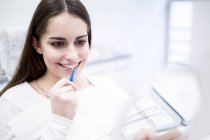 Young woman using interdental brush and looking in mirror in hospital. — Stock Photo