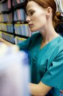 Nurse searching through medical records in store room. — Stock Photo