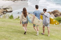 Junge Erwachsene laufen mit Surfbrettern am Strand. — Stockfoto