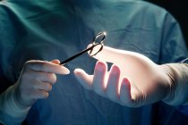 Ausgeschnittene Ansicht des Assistenten, der dem Chirurgen während der Operation eine Pinzette reicht. — Stockfoto