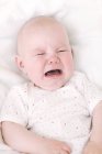 Bebé infeliz llorando en la cama . - foto de stock