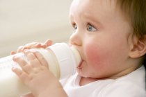 Retrato del niño bebiendo leche del biberón . - foto de stock