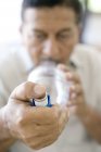 Зрілий чоловік використовує розгалужувач астми з синім інгалятором астми . — стокове фото