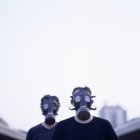 Two men wearing gas masks in city. — Stock Photo