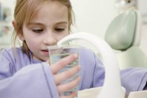 Girl in dental treatment room filling glass with antimicrobial mouth rinse. — Stock Photo