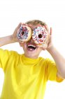 Junge spielt und Augen mit Donuts bedeckt. — Stockfoto