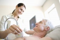 Senior patient undergoing heart ultrasound scanning by female doctor. — Stock Photo