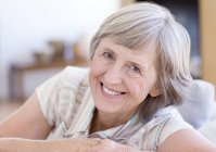 Porträt einer glücklichen Seniorin, die es sich auf dem Sofa gemütlich macht. — Stockfoto