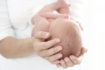 Primer plano de las manos de la madre sosteniendo al bebé recién nacido . - foto de stock