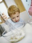 Garçon d'âge préscolaire mélangeant les ingrédients dans un bol . — Photo de stock