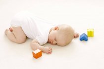 Menina bebê dormindo no chão cercado por blocos de brinquedo . — Fotografia de Stock