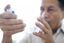 Homem maduro usando espaçador de asma com inalador de asma azul . — Fotografia de Stock
