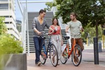 Friends walking with bikes and coffee on street. — Stock Photo