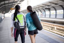 Жінки зі спортивним обладнанням на залізничній платформі — стокове фото
