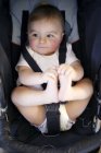 Baby boy strapped into car safety seat. — Stock Photo