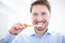 Середній дорослий чоловік чистить зуби, портрет . — стокове фото