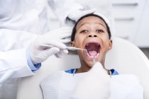 Médicos examinando dientes de niño en la clínica . - foto de stock