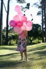 Mujer sosteniendo globos rosados en el parque . - foto de stock