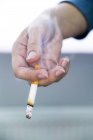 Rauch steigt aus brennender Zigarette in weiblicher Hand auf. — Stockfoto