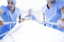 Equipo de emergencia empujando camilla del hospital con paciente en corredor . - foto de stock